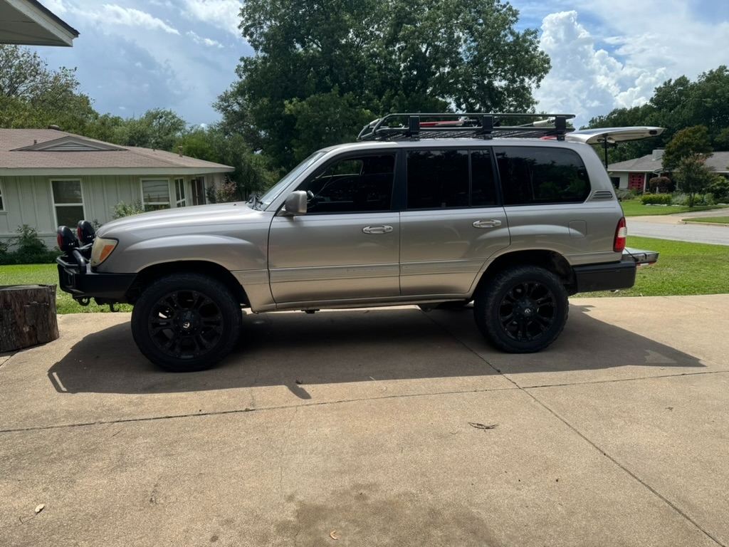 2006 Land Cruiser, driver-side profile in driveway, titanium silver with ARB front bumper and roof rack